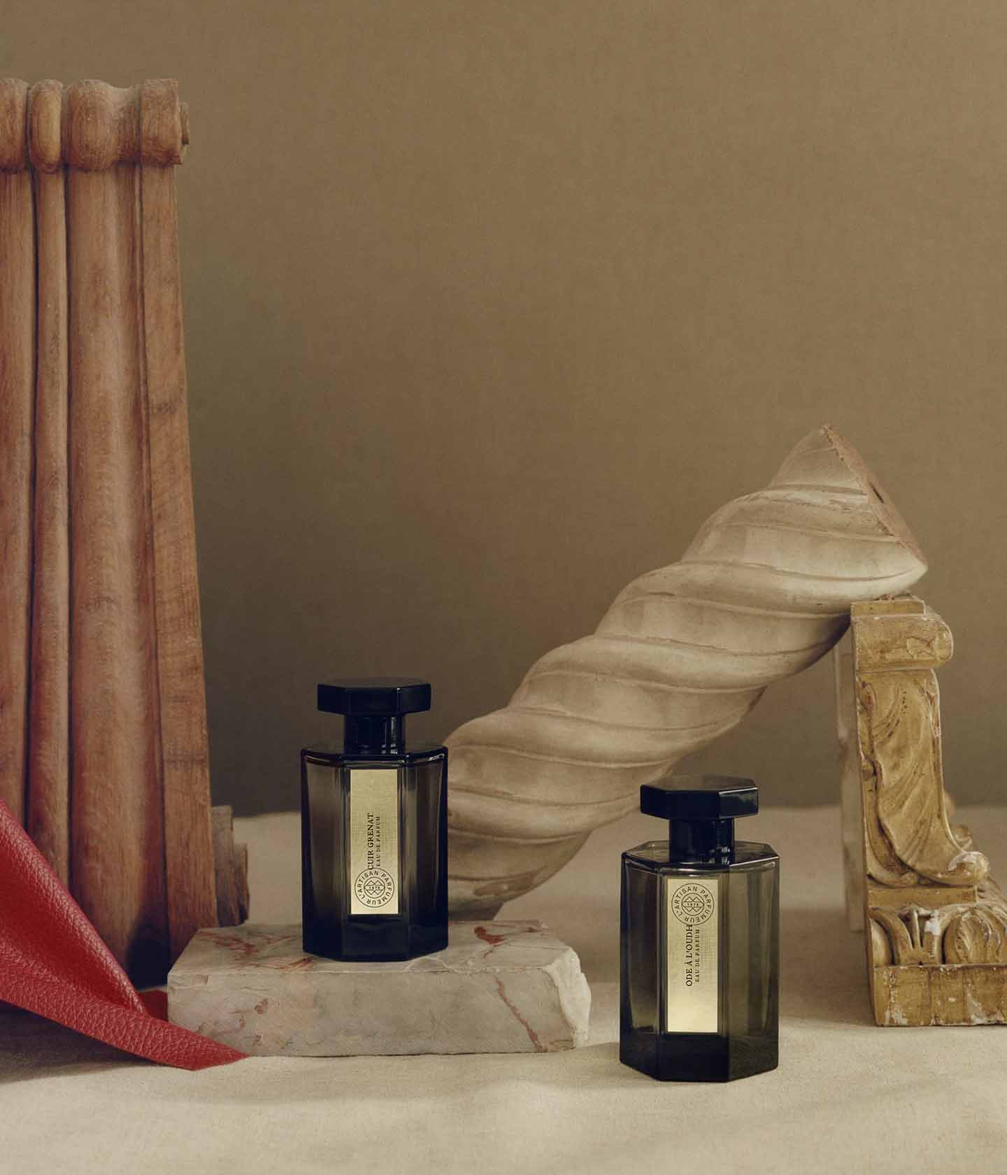 L'Artisan Parfumeur Les Merveilles, zwei Flakons zwischen gedrechselten Steinsäulen