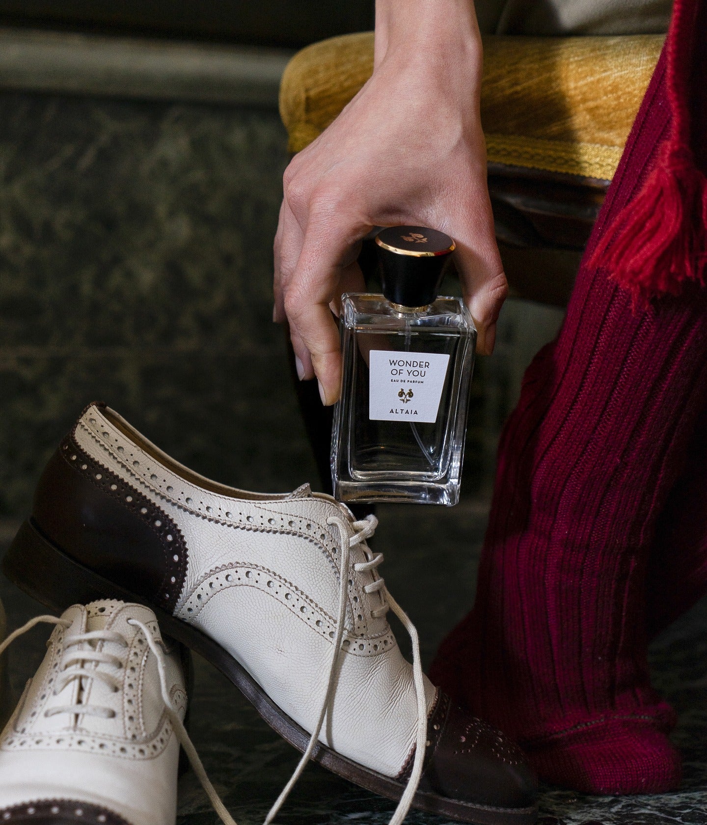 Altaia Flakon, in der Hand über zweifarbigen Brogues