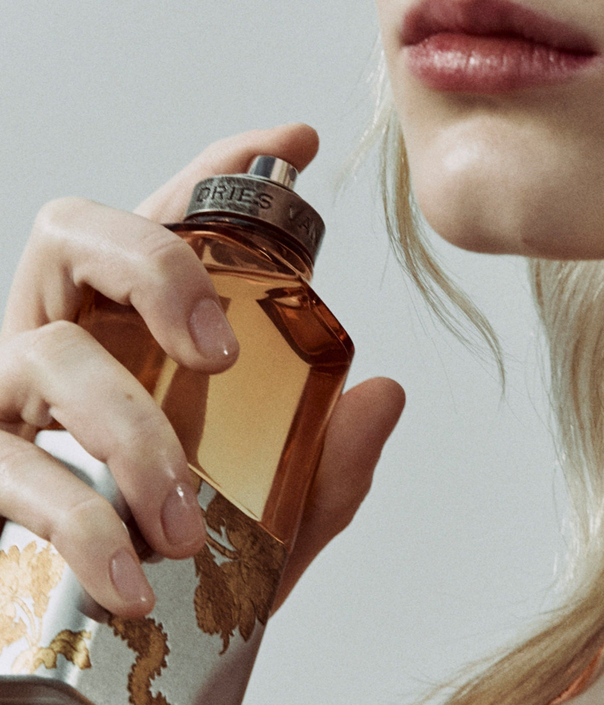 Dries Van Noten Flakon in der Hand vor den Lippen einer Frau