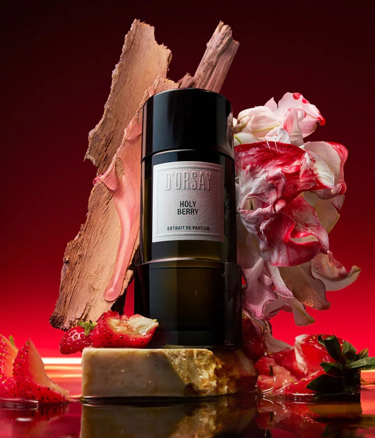 D’Orsay Extrait de Parfum Holy Berry zwischen Rindenstücken, Erdbeeren und Blüten vor rotem Grund