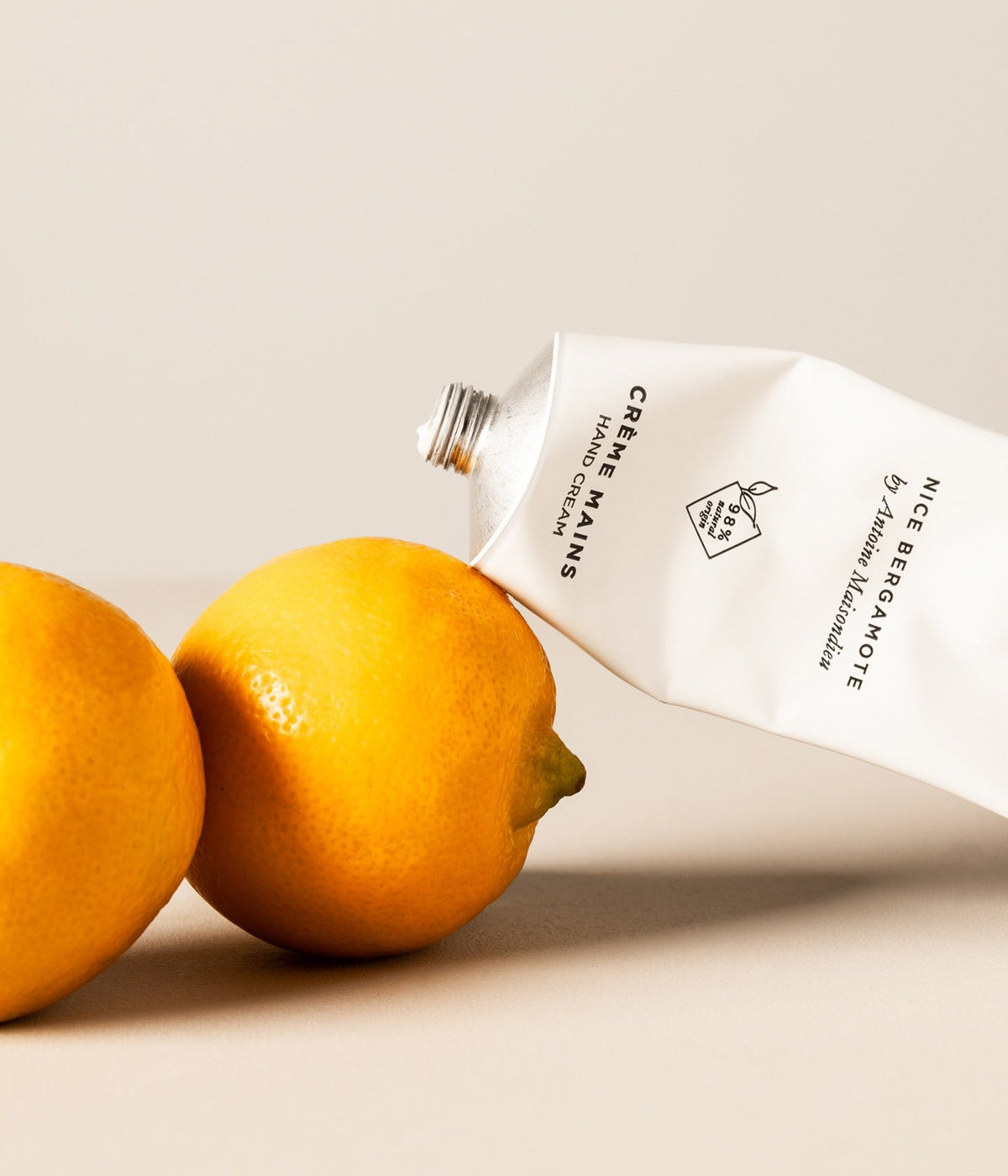 Essential Parfums Handcreme Nice Bergamote, Tube liegend neben Zitrusfrüchten