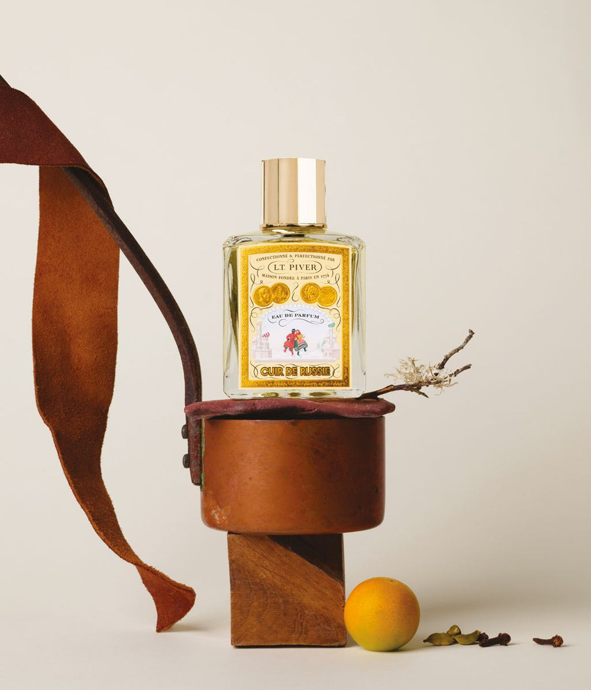 Eau de Parfum Cuir de Russie – L.T. Piver, Stillleben mit Lederriemen und Holzsockel