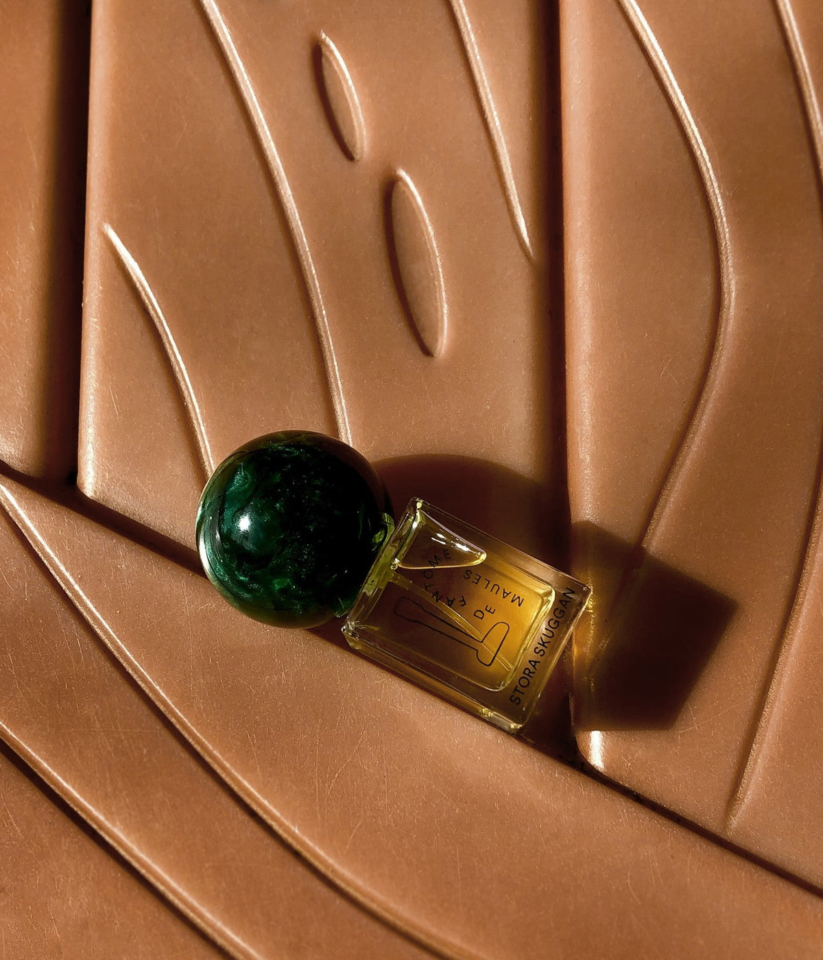 Stora Skuggan Eau de Parfum Fantôme de Maules auf einer geschwungenen, kupferfarbenen Reliefoberfläche