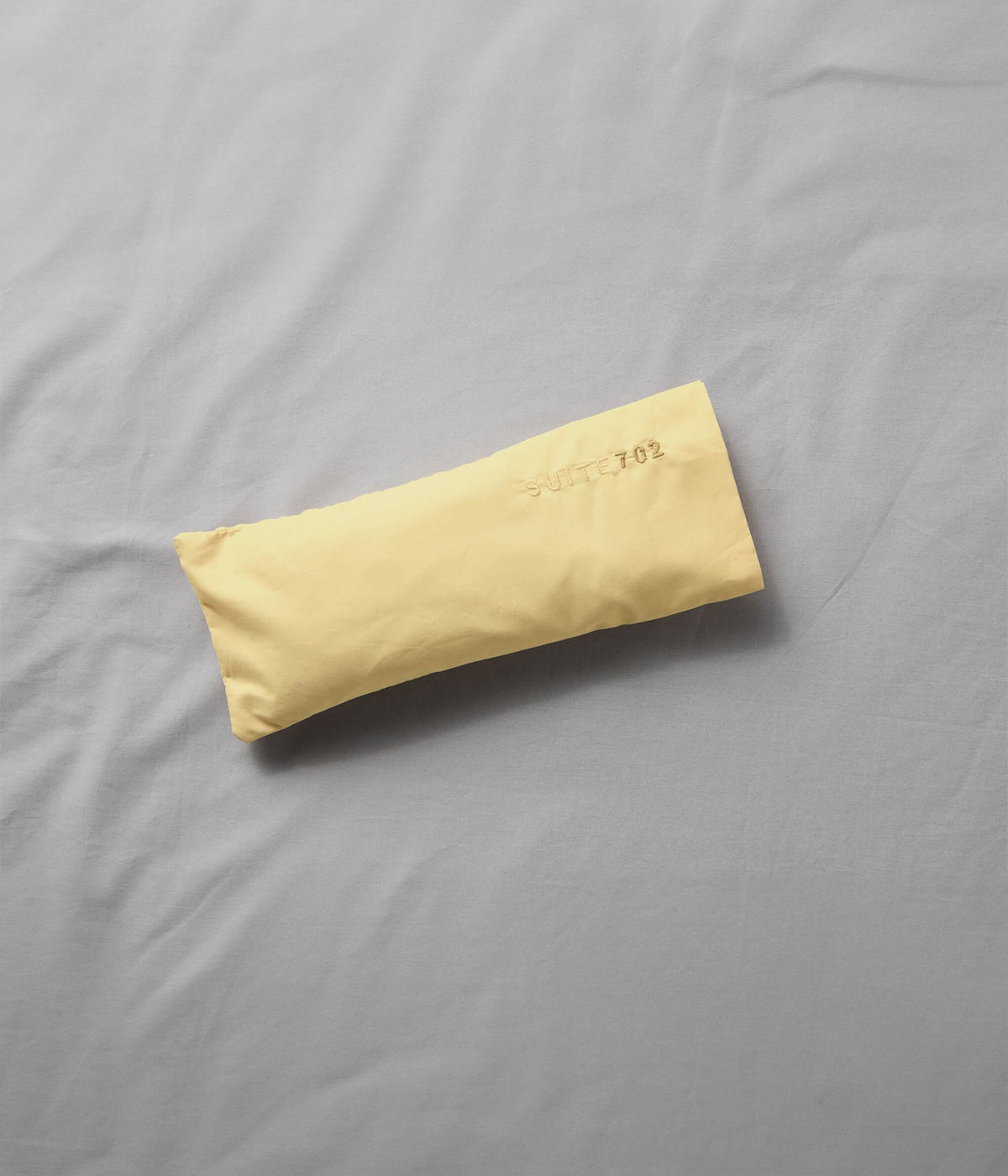 Augenkissen Butter Yellow – Suite702, auf grauer Bettwäsche